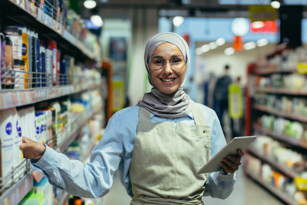 A young muslim retail assistant stands in the household chemical aisle in a supermarket